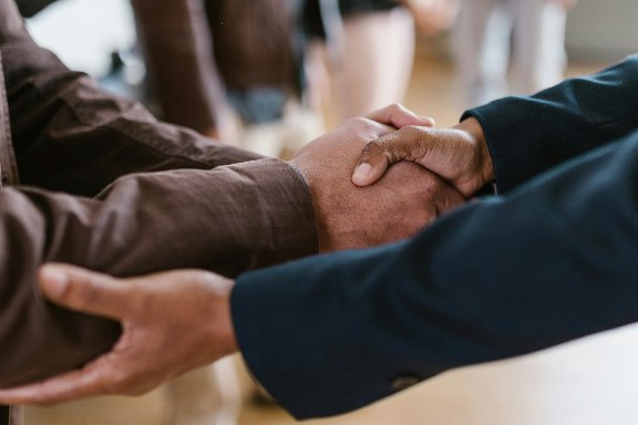Two people clasping hands warmly in a supportive handshake